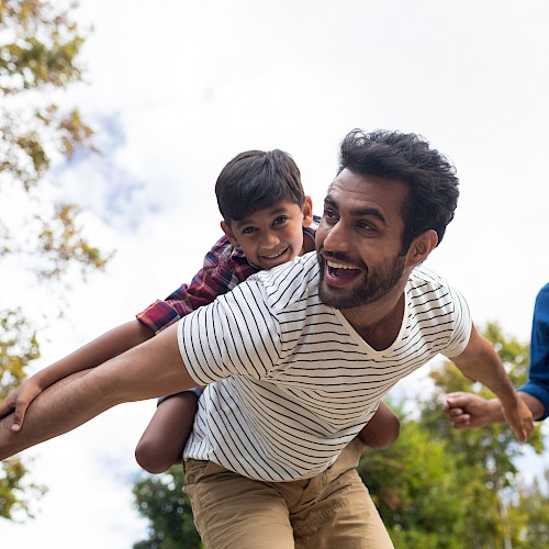 Two young ethnic minority men, one in a white t shirt with a young boy on his back