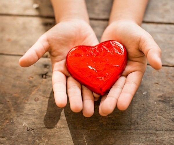 Child's hands holding a red heart