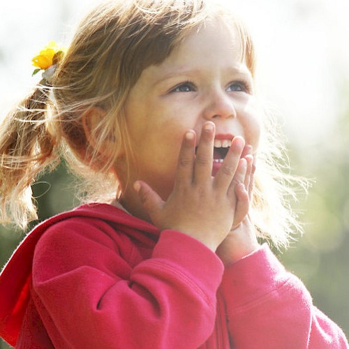 Young laughing girl with her hands to her mouth