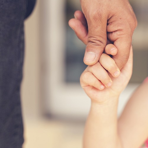Close up of young child's hand gripping an adult's finger