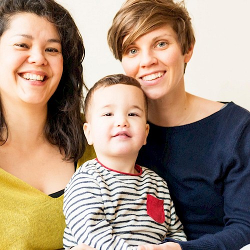 Gay female couple with a young boy on their lap, smiling