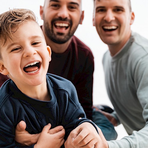 Gay male couple with young boy laughing