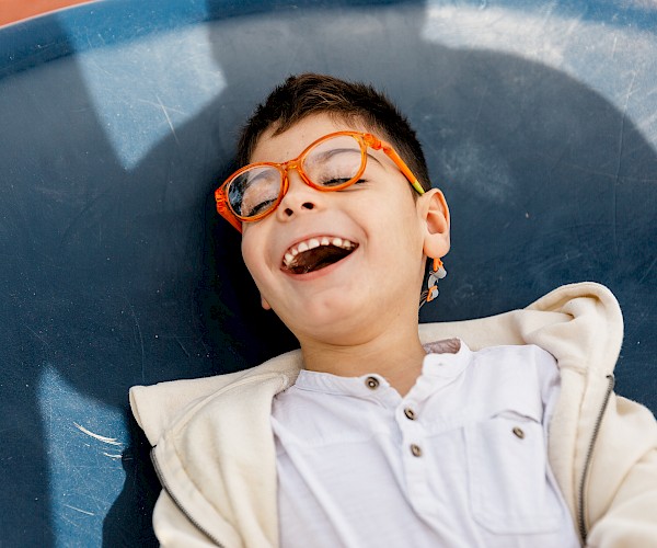 Special needs boy with orange glasses laughing
