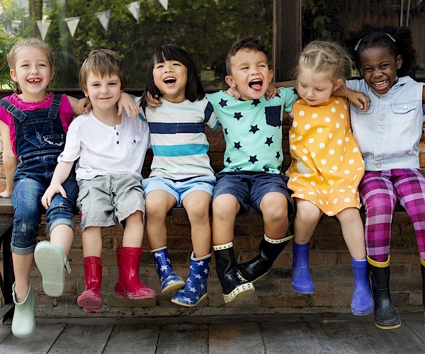 Young ethnic minority children sitting on a bench with arms around each other