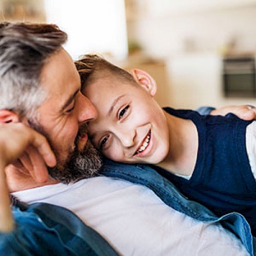 Young boy laying on a man's chest smiling