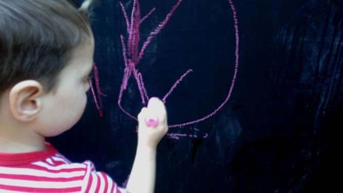 Young boy drawing on a chalk board